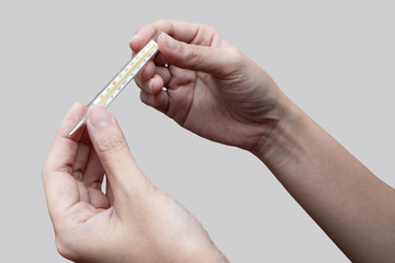 Closeup of two hands holding clinical thermometer and looking on it for checking temperature. Diagnosis and test COVID-19.