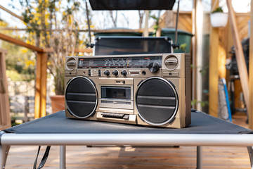 Ghettoblaster on lounger on wooden porch in sunlight