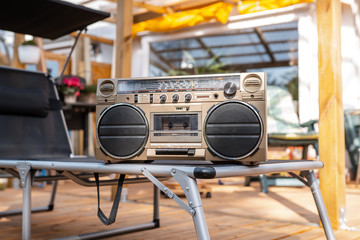 Ghettoblaster on lounger on wooden porch in sunlight