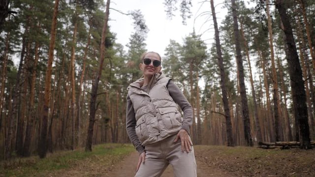 A woman make a fun dance in 4k slow motion next to a pine forest