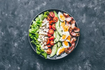 Dekokissen Cobb salad with chicken, avocado, tomatoes, eggs, bacon and cheese with sauce on a black  table top view © Anntuan