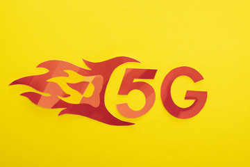 Fototapeta na wymiar top view of red 5g with flame lettering on yellow background