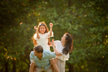 Fototapeta premium Happy family playing on the grass in the park at sunset. The concept of a happy family.