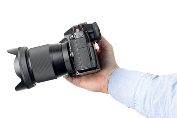 Small mirrorless photo camera in hand on a white background.