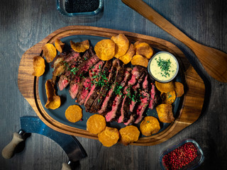 Medium grilled steak with sweet potato chips and freshmade mayonaise served on a wooden board