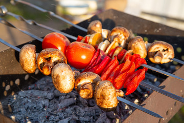 champignons, peppers and tomatoes on skewers fried on hot coals