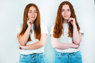 two redheaded young women both touching faces with their hands standing on isolated white backgroung