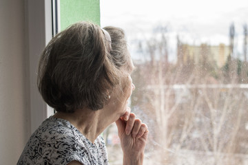  sad lonely old woman look next to  window allone depressed abandoned coronavirus stay home  - obrazy, fototapety, plakaty