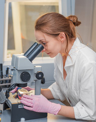Girl scientist working in a laboratory with an electron microscope in the foreground