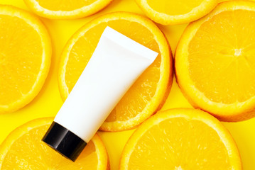 Natural vitamin c skincare products with fresh juicy orange fruit slice on orange background. Cosmetic beauty product branding mock-up for moisturizing cream, lotion, serum or essential oil
