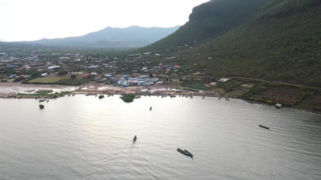 Flying over fishing boats at the Kenyan coast. Boat coming ashore, drone flies over a small village, drone stock footage by DroneRune