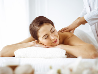 Fototapeta na wymiar Beautiful brunette woman enjoying back massage with closed eyes. Spa and medicine concept