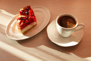Concept - close up of a mug with coffee and cake on the table.
