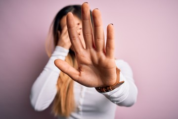 Obraz na płótnie Canvas Young beautiful blonde woman with blue eyes wearing white t-shirt over pink background covering eyes with hands and doing stop gesture with sad and fear expression. Embarrassed and negative concept.