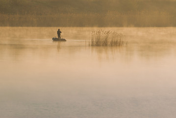 Obraz na płótnie Canvas angler fishing on a boat in the morning