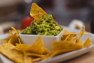 Chips decorated in a Plate with Bowl full of Guacamole surrounded 