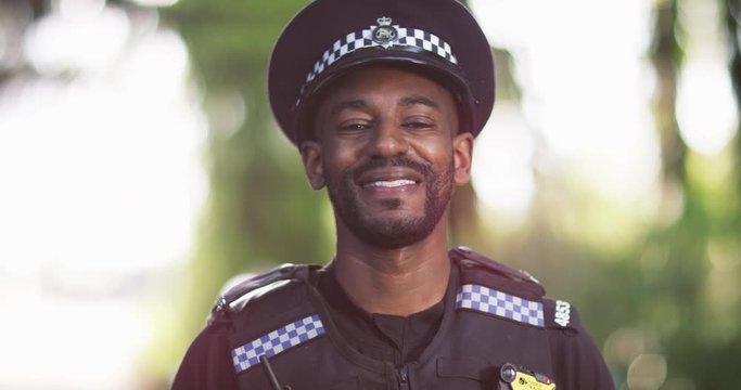 4K Close up portrait of smiling policeman outdoors with blurred background. Slow motion.