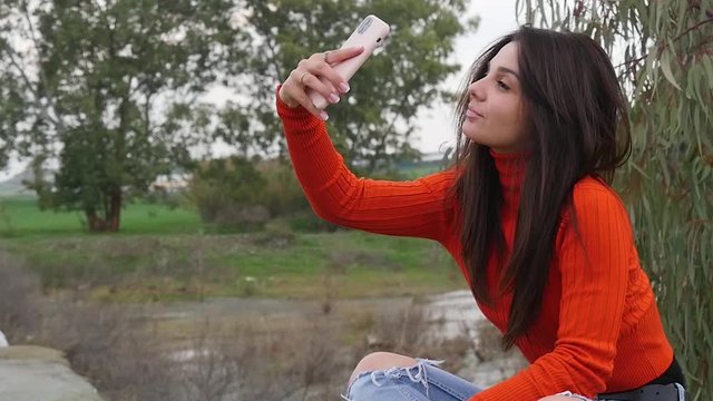 Female Model Taking Multiple Selfies On Phone In Park In Slow Motion