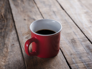 Obraz na płótnie Canvas red mug of black coffee isolated on a wooden table