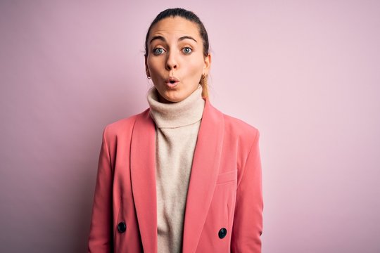 Young beautiful blonde businesswoman with blue eyes wearing elegant pink jacket afraid and shocked with surprise expression, fear and excited face.
