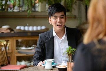 Happy young Asian business couple together at the coffee shop