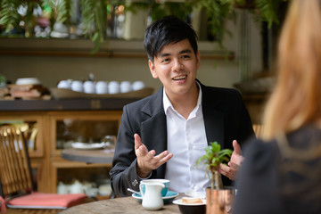 Happy young Asian business couple together at the coffee shop
