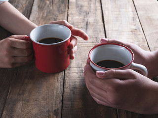 two people having a cup of coffee, only hands and mugs are shown