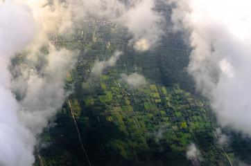 Aerial view of green fields looking through the clouds