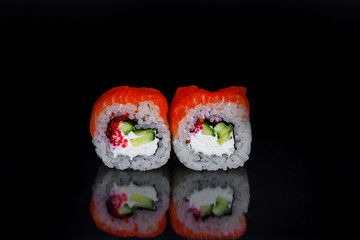 Tradishional Japanese sushi with red salmon, caviar, cucamber and cheese on black glass surface with reflection. Asian food concept.