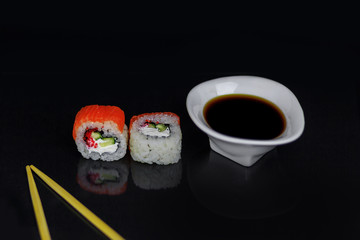 Tradishional Japanese sushi with red salmon, caviar, cucamber and cheese on black glass surface with reflection. Asian food concept.