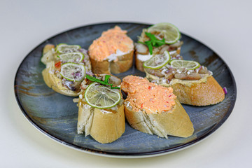Toat bread with lime, fish paste. Restaurant dish on a big plate on white background.