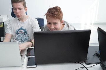 the boys are working with a laptop. students study in the classroom. Teenagers work on their laptop. Design lesson at school.  