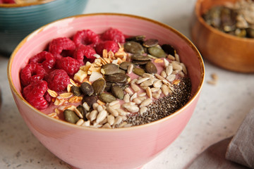 Healthy food - smoothie bowl topped with raspberries, granola, seeds and chia. Closeup view