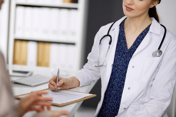 Doctor and patient discussing current health examination while sitting in clinic. Perfect medical...
