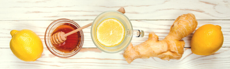 Drink hot tea with ginger-lemon and honey on white wooden background, prevention of colds. Selective focus