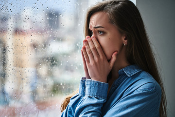 Portrait of a young stressed sad lonely melancholy shocked woman covering mouth with hands during...