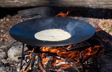 Open Fire cooking. Pancekes on a cast iron pan. Outside, nature, tracking, bush Craft. Close upp.