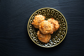 Oriental food concept homemade Chinese Sesame Cookie in green ceramic plate on black slate stone board with copy space