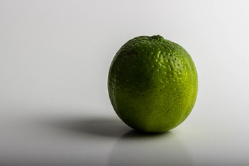 One delicious and sour green lime is laying on a table against a white background.