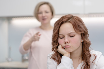 Mom scolds the daughter of a teenager while she  ignores the mother. Relationship problem concep