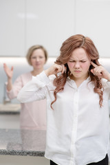 The teenage girl covered her ears with her hands so as not to hear her mother scolding her. Problem with parents concept