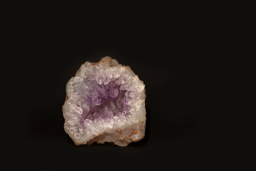 Untreated mineral amethyst quartz is a soft lilac color, isolated on a black background. Semiprecious stone. House decoration
