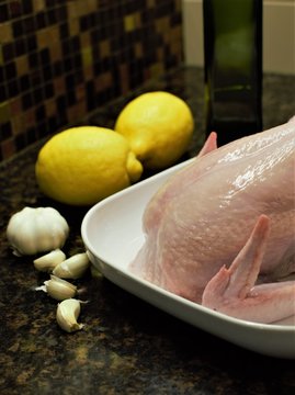 Raw whole chicken ready for cooking or roast on kitchen table over dark background. Side or top  view.