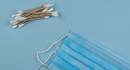 Flat lay composition with medical mask and natural cotton sticks on blue background. antiviral respiratory bandage face