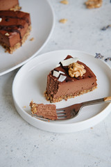 Piece of homemade chocolate raw vegan cake - healthy dessert made from coconut butter, cashew, cacao, walnut