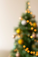 Beautiful vertical background of a blurry Christmas tree with lights and yellow balls, space for text