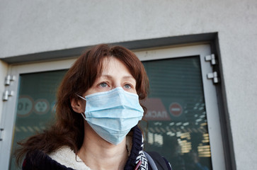 Woman wearing hygienic mask to prevent the Coronavirus. People in masks The outbreak of Novel Corona virus (2019-nCoV) in Europe. Concept of coronavirus quarantine. Air pollution