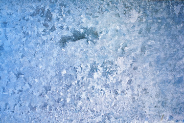 Abstract and fantastic icy patterns on frozen window glass. Hoarfrost effect texture. Blue winter background. Clear frosty ornament on surface. Christmas or winter backdrop. Rime or frost structure