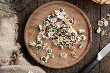 Obraz na płótnie Canvas Common daisy flowers on a cutting board, top view