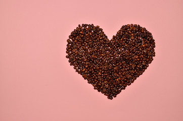 Love sign of coffee beans lying on pink background